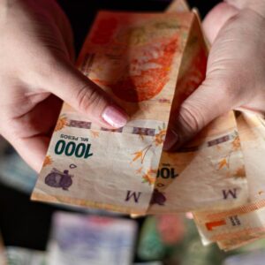 Hands holding Argentine peso banknotes, showcasing currency details in Buenos Aires.